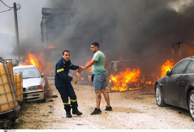 Συγκλονιστική φωτογραφία πυροσβεστη που προσπαθει να απομακρύνει πολιτη που βλέπει το αυτοκίνητο του να φλέγεται